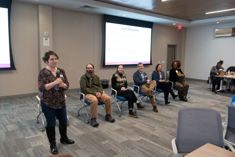 A panel of men and women in front of a projector screen.