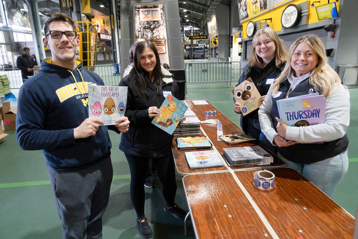 A small group of people holding up children's books.