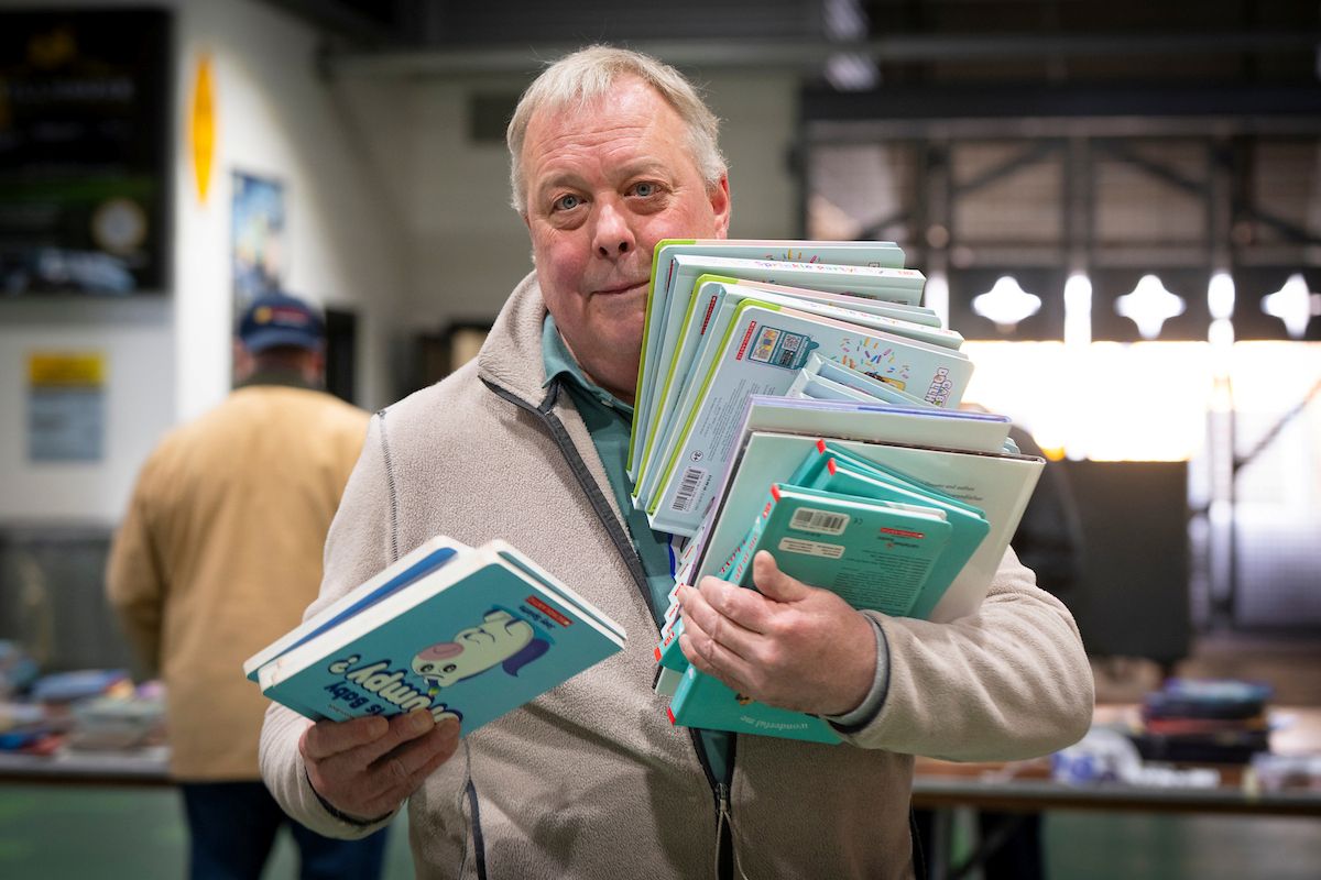 Man in a tan coat holding books