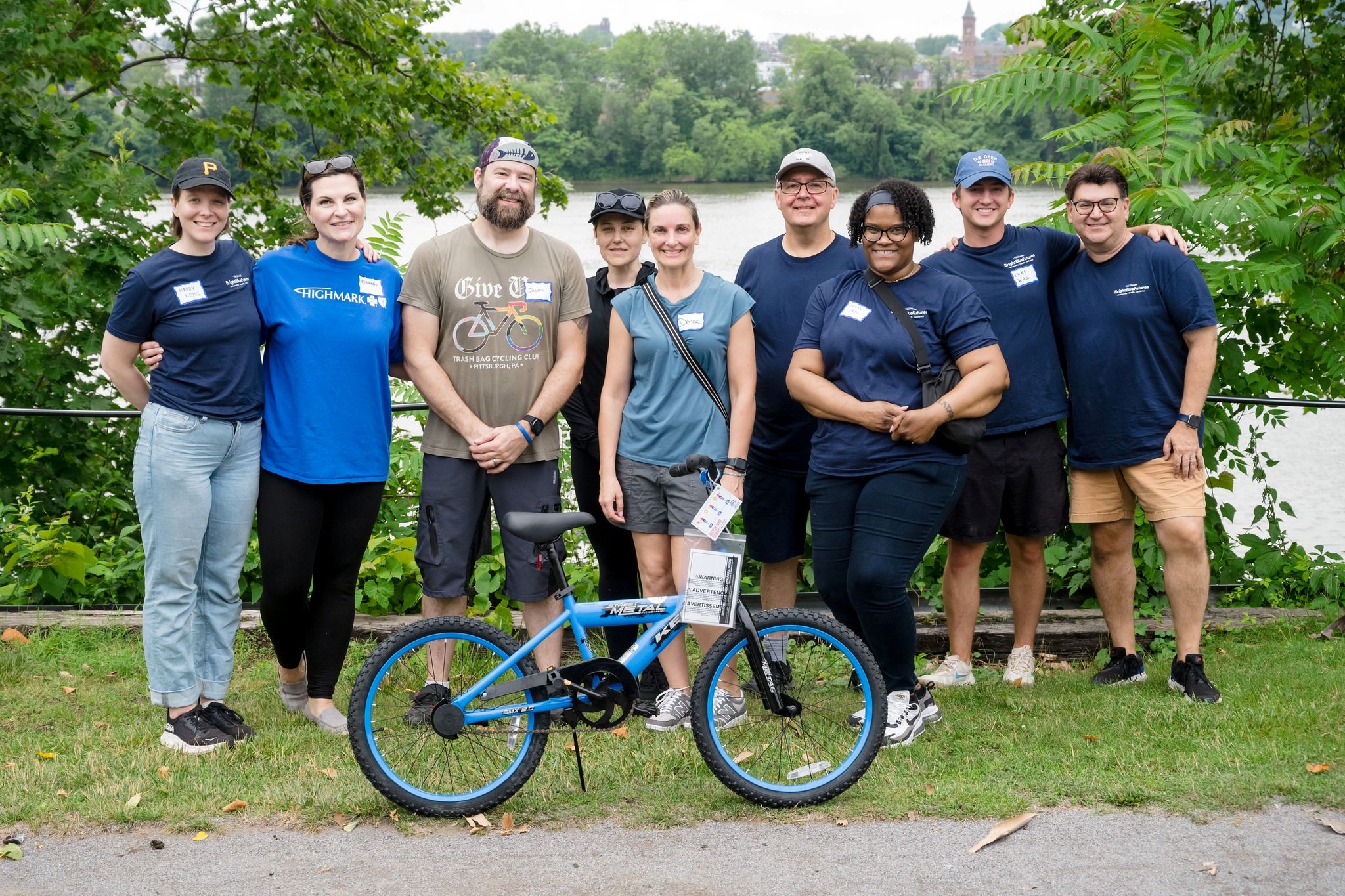 Group of men and women with a blue bicycle in front of them.